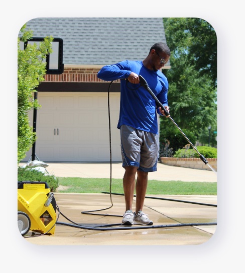 Man using pressure washer to clean the driveway